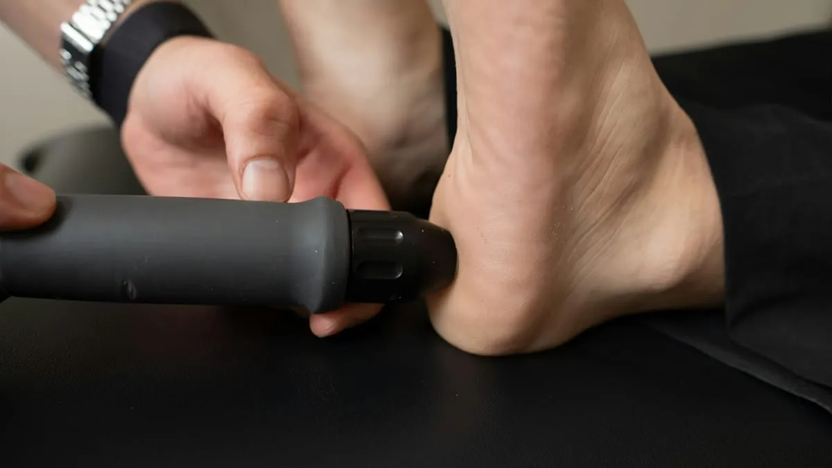 A shockwave applicator held against the back of a heel